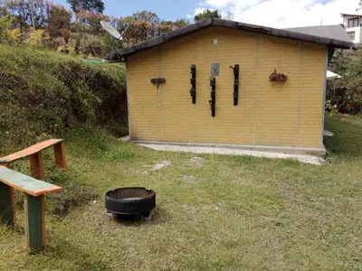 a small yellow building with a black suitcase in the yard at Casa Campestre en Guarne in Guarne