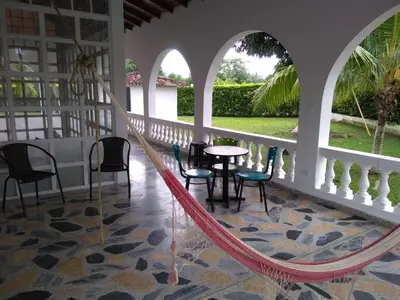 a hammock in a porch with chairs and a table at Casa campestre con piscina, jacuzzi y bbq in La Dorada