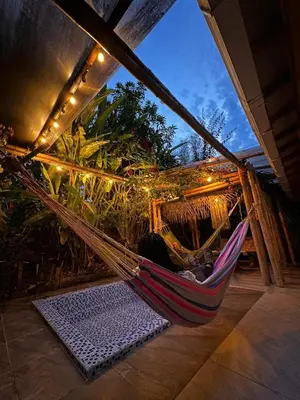 a hammock on a porch with plants and lights at Mamaquilla Grupal Glamping in Jardin