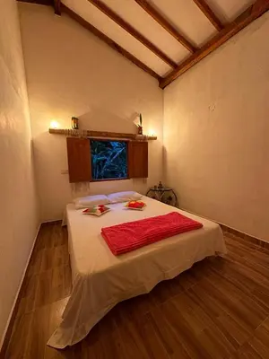 a bedroom with a bed with a red blanket on it at Mamaquilla Grupal Glamping in Jardin