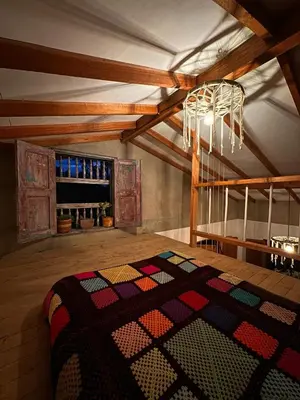 an attic room with a bed and a chandelier at Mamaquilla Grupal Glamping in Jardin