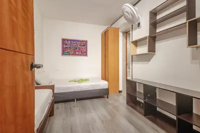 a small room with two beds and a closet at Hostal Machu Picchu Medellín in Medellín