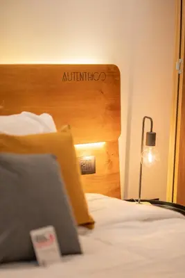 a bedroom with a bed with a wooden headboard and a lamp at Autenthico Local Stay Hotel Envigado in Envigado