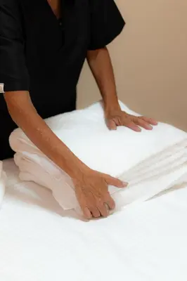 a man is putting white sheets on a bed at Autenthico Local Stay Hotel Envigado in Envigado