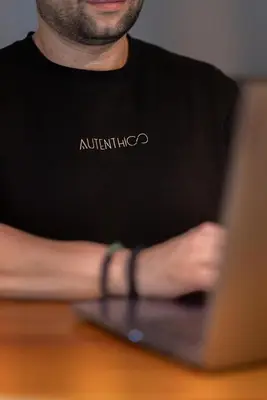 a man sitting at a table with a laptop computer at Autenthico Local Stay Hotel Envigado in Envigado