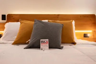 a bed with two pillows and a sign on it at Autenthico Local Stay Hotel Envigado in Envigado
