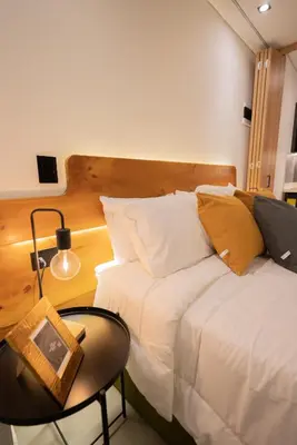 a bedroom with a white bed with a table and a chair at Autenthico Local Stay Hotel Envigado in Envigado