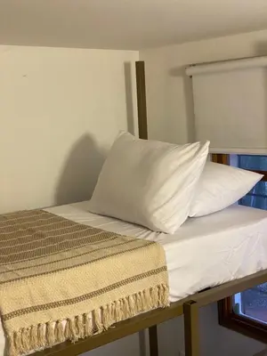 a bed with white sheets and a pillow on it at El Solar Hostel - Comuna 13, graffitour in Medellín