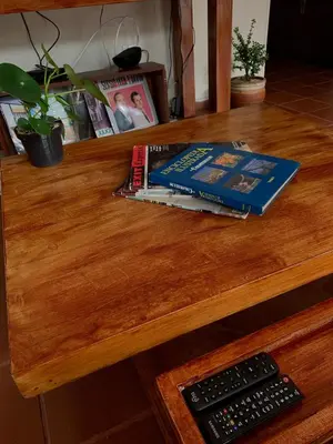 two books on a wooden table with a remote control at El Solar Hostel - Comuna 13, graffitour in Medellín