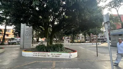 a man walking past a tree in a park at Apartamento Simón Bolívar in Itagüí