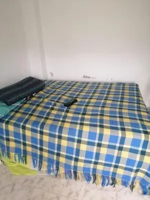 a bed with a blue and yellow plaid sheet on it at Delicias del rio in San Rafael