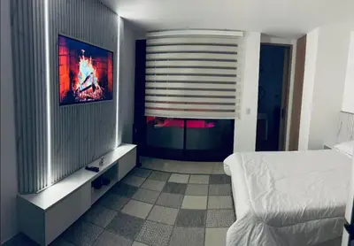 a bedroom with a bed and a flat screen tv at Aparta- estudio de lujo con jacuzzi in Medellín