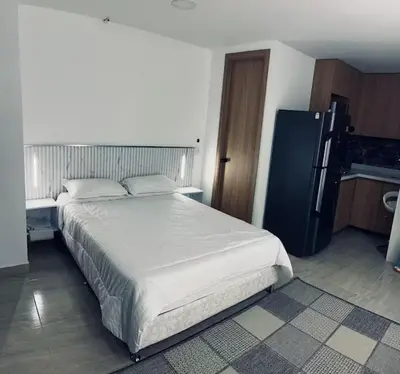 a bedroom with a large white bed and a refrigerator at Aparta- estudio de lujo con jacuzzi in Medellín