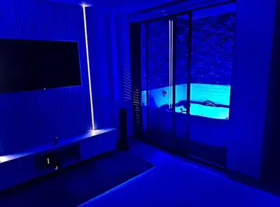 a blue room with a television and a tub with a window at Aparta- estudio de lujo con jacuzzi in Medellín
