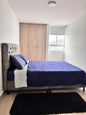a bedroom with a bed with blue sheets and a window at Central, Universidades y Centro Comercial in Manizales