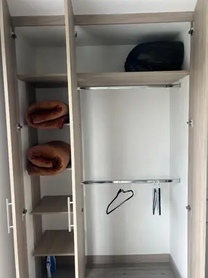 a walk in closet with a refrigerator and wooden shelves at Central, Universidades y Centro Comercial in Manizales