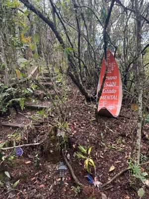a sign on the side of a trail in the woods at Bosque Encantado Story in Medellín