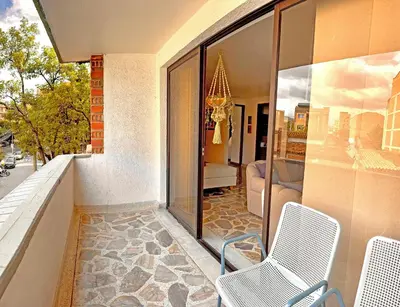 a balcony with two chairs and a living room at Apartamento Stay Medellín Laureles in Medellín
