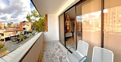a balcony with two chairs and a view of a city at Apartamento Stay Medellín Laureles in Medellín