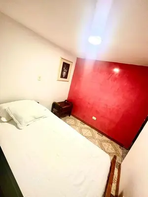 a room with a bed with a red wall at Apartamento en Belén la palma medellin in Medellín