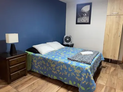 a bedroom with a bed and a dresser with a lamp at Loft Belén cerca a Unicentro y Unidad Deportiva Belén Sofá cama in Medellín