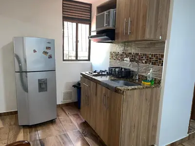 a kitchen with a white refrigerator and wooden cabinets at Loft Belén cerca a Unicentro y Unidad Deportiva Belén Sofá cama in Medellín