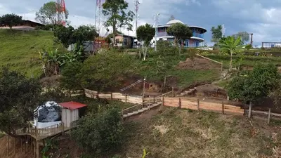 a farm with a fence and a house on a hill at Bed and bath at Villacarolina in Titiribí