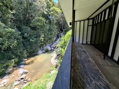 a house with a wooden walkway next to a river at Cabaña sol wifi jacuzzi charcos parking in Barbosa