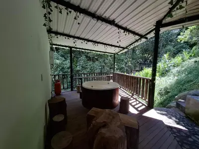 a screened in porch with a tub on a deck at Cabaña sol wifi jacuzzi charcos parking in Barbosa