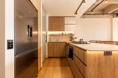 a kitchen with wooden cabinets and a stainless steel refrigerator at Central, Modern Apartment in Envigado in Envigado