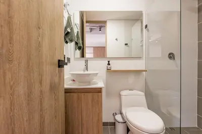 a bathroom with a toilet and a sink and a mirror at Central, Modern Apartment in Envigado in Envigado