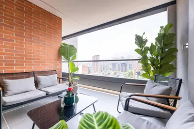 a balcony with a couch and chairs and a large window at Spacious 2H Modern in Envigado in Envigado
