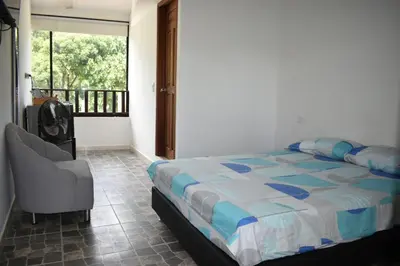a bedroom with a bed and a chair and a window at hotel bocas del cauca in Tarso