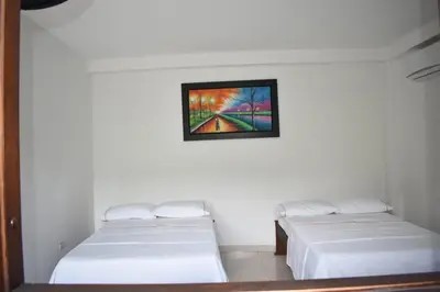 two beds in a room with a painting on the wall at hotel bocas del cauca in Tarso