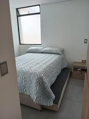 a bed with a black and white comforter and a window at A home away from home! in Medellín