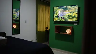 a bedroom with a green wall with a tv above a fireplace at Olivo House Casa Hotel in Envigado