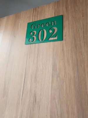 a green sign on a wooden door with the words green at Moderno & Central, descubre medellin desde Laureles in Medellín