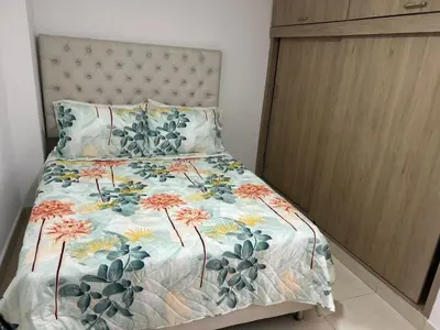 a bedroom with a bed with a floral bedspread at precioso apto para su estadia in Medellín