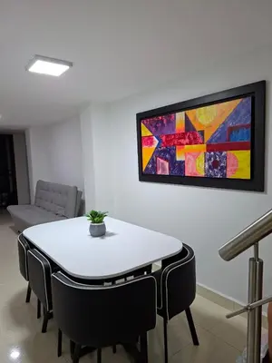 a table and chairs in a room with a painting on the wall at precioso apto para su estadia in Medellín