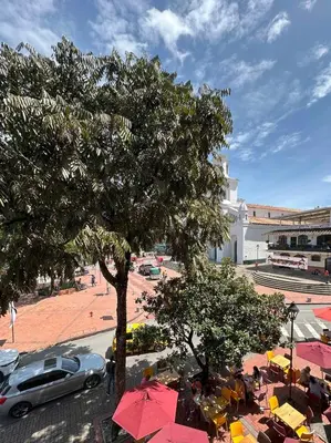 a car parked under a tree near a street with umbrellas at Apartamento central y espacioso in Marinilla