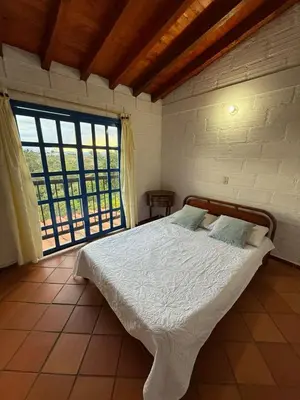 a bedroom with a bed and a large window at Finca Marinilla in Marinilla