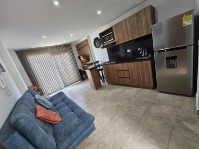 a living room with a blue couch and a kitchen at Apto Confortable en Zona Exclusiva de Laureles Medellín 401 Tranquilidad y cerca a todo in Medellín