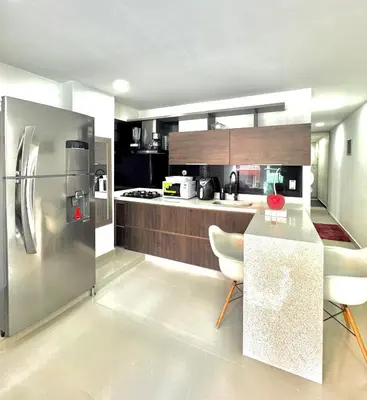 a kitchen with a stainless steel refrigerator and a table at Apartamento Acogedor y Tranquilo in Sabaneta