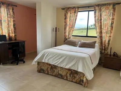 a bedroom with a bed and a desk and a window at Casa Alma in Guarne