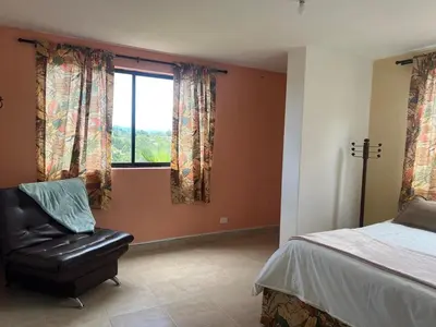 a bedroom with a bed and a chair and a window at Casa Alma in Guarne