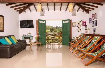 a living room with green doors and a couch at Blomst Casa Hostal in Jericó
