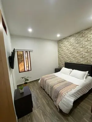 a bedroom with a large bed and a brick wall at Finca a 3 minutos aeropuerto jmc in Rionegro