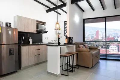 a kitchen with a bar and a couch in a room at Cozy Laureles Retreat, Stadium Vicinity in Medellín