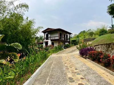 a walkway leading to a house in a garden at Outstanding FarmHouse jacuzzi & pool near Medellin in Venecia