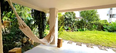 a hammock on a porch with a view of a yard at Macondo House in Medellín
